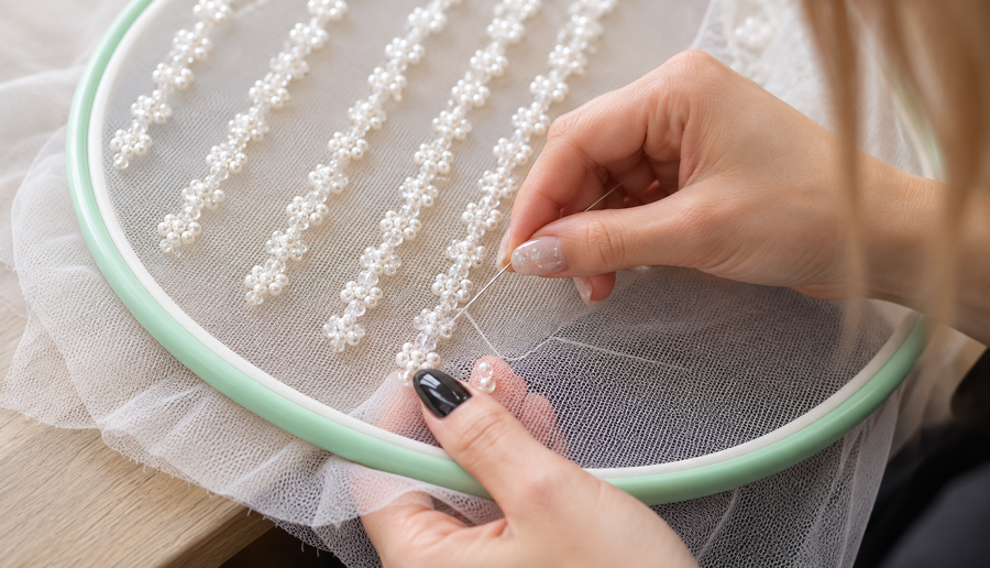Pearls being sewn onto tulle by hand